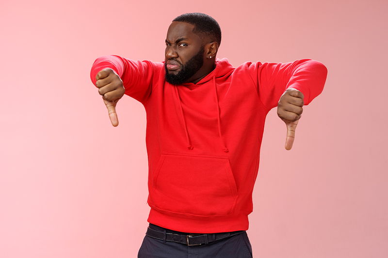 man holding two thumbs down disappointed expression